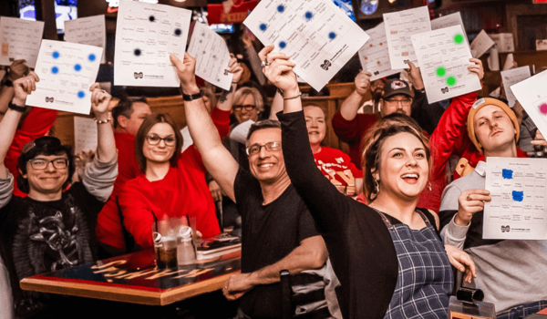 A group of people sitting in front of tables holding up papers.