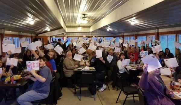 A group of people sitting around tables holding papers.